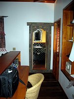 The doorway to the bathroom, also showing then desk behind the headboard.  
